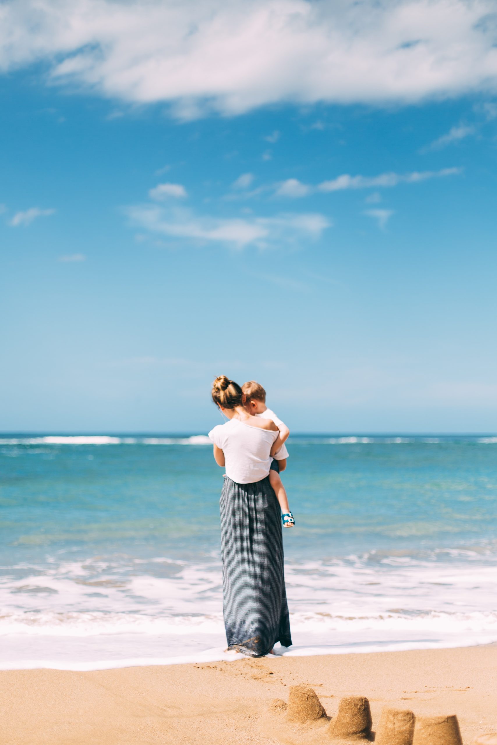 Photo par Daiga Ellaby woman carrying toddler on seashore