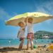 two children playing under umbrella on seashore